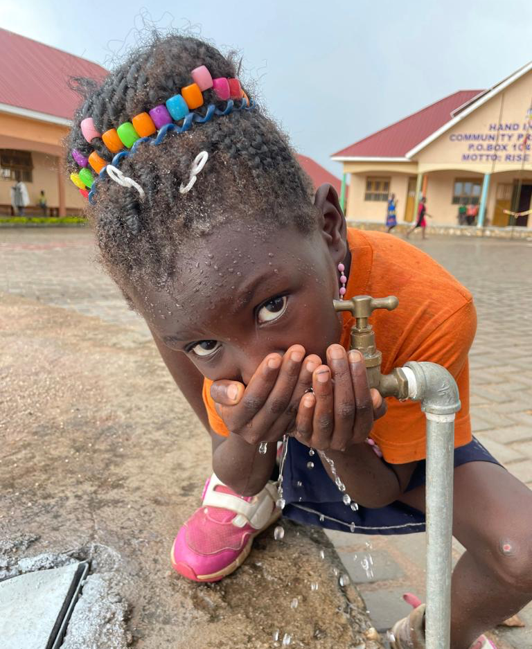 Mädchen trinkt aus einem Wasserhahn in Afrika