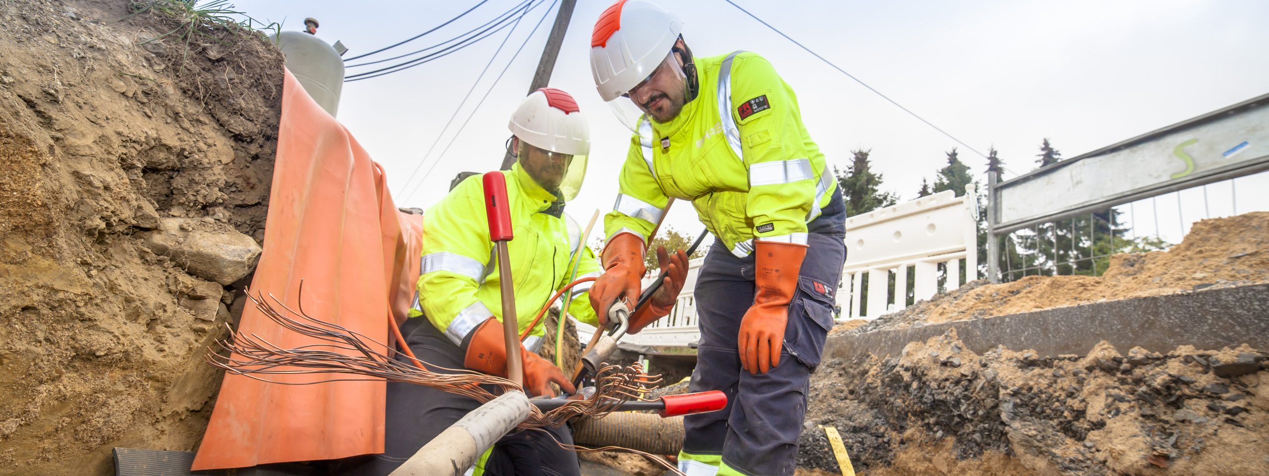 Monteure verlegen NS-Kabel auf einer Baustelle