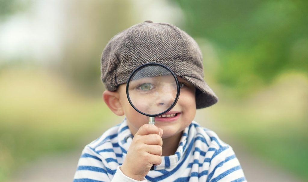 Kind guckt durch eine Lupe.