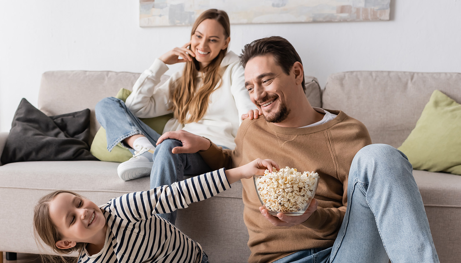 Familie sitzt zusammen auf dem Sofa und freut sich auf den Fernsehabend.