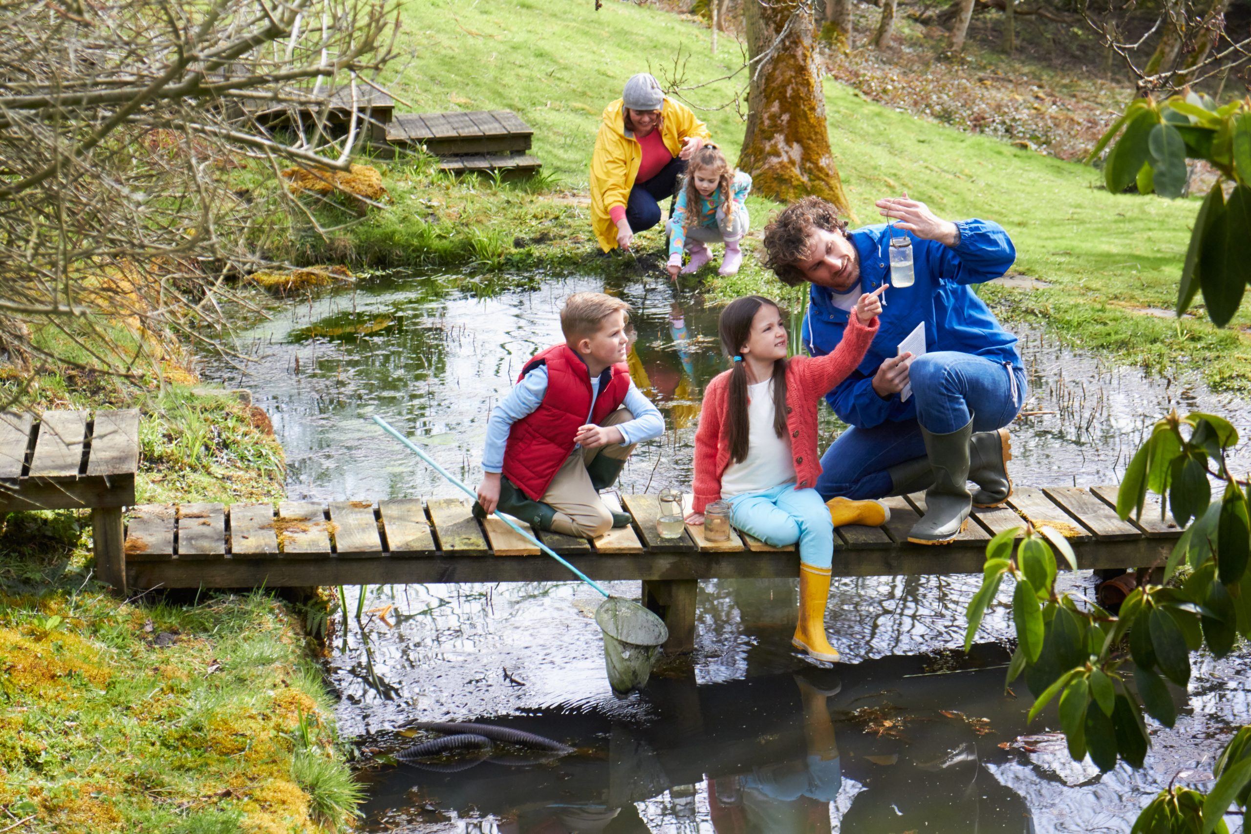 Kinder sammeln Wasserproben an einem Teich.
