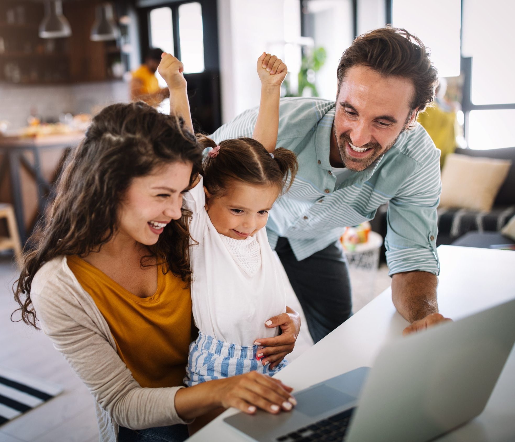 Familie sitzt vor dem Laptop und freut sich.