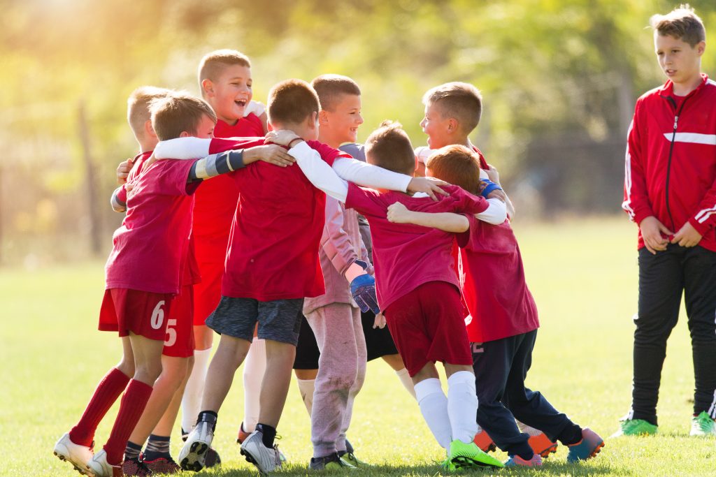 Kinder spielen Fußball und freuen sich über den Sieg.