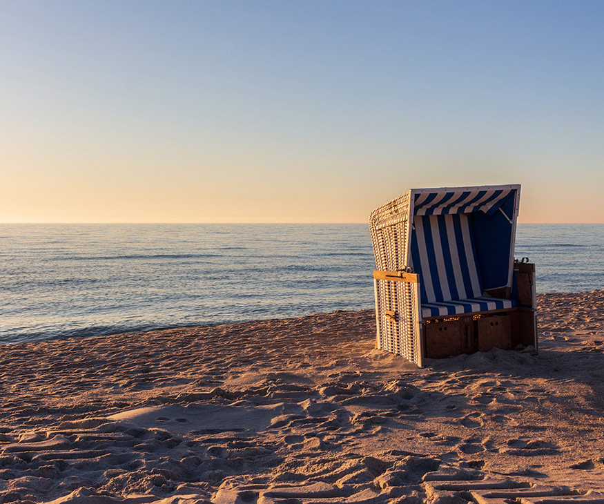 Strandkorb an einem Strand bei Sonnenuntergang.