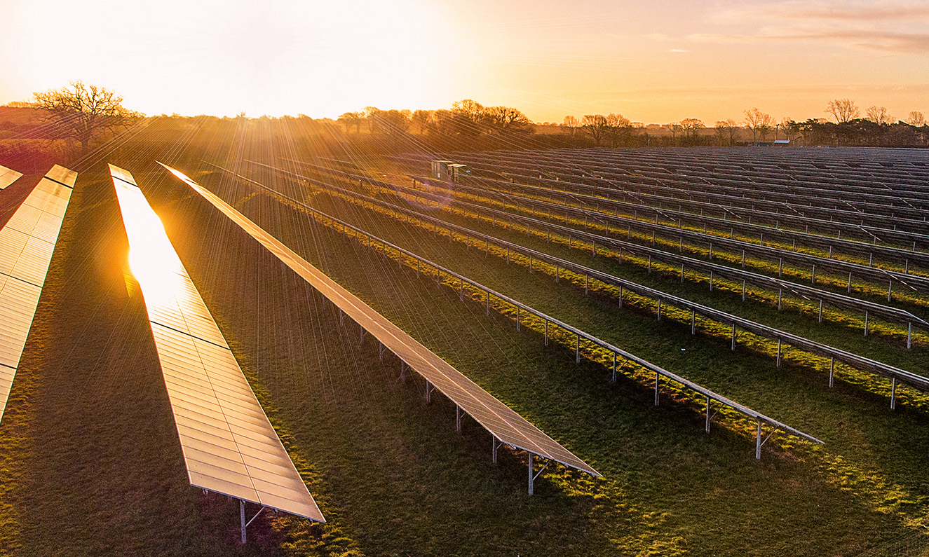 Photovoltaik-Freiflächenanlage auf einer Wiese bei Sonnenuntergang