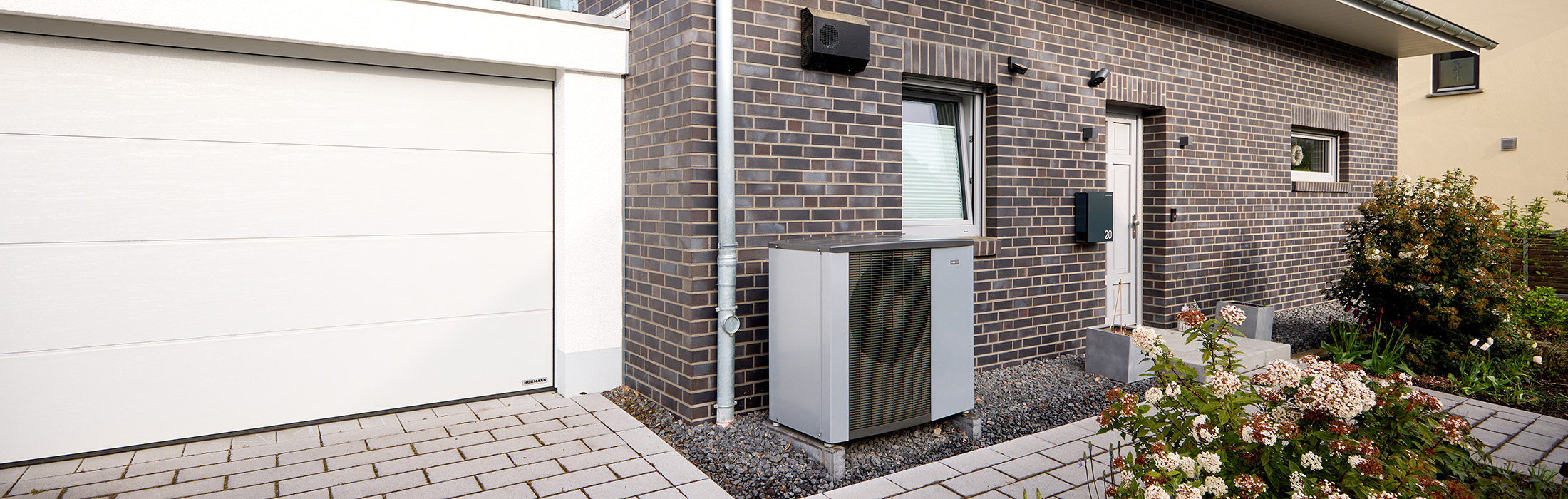 Wärmepumpe vor Haus mit Garage