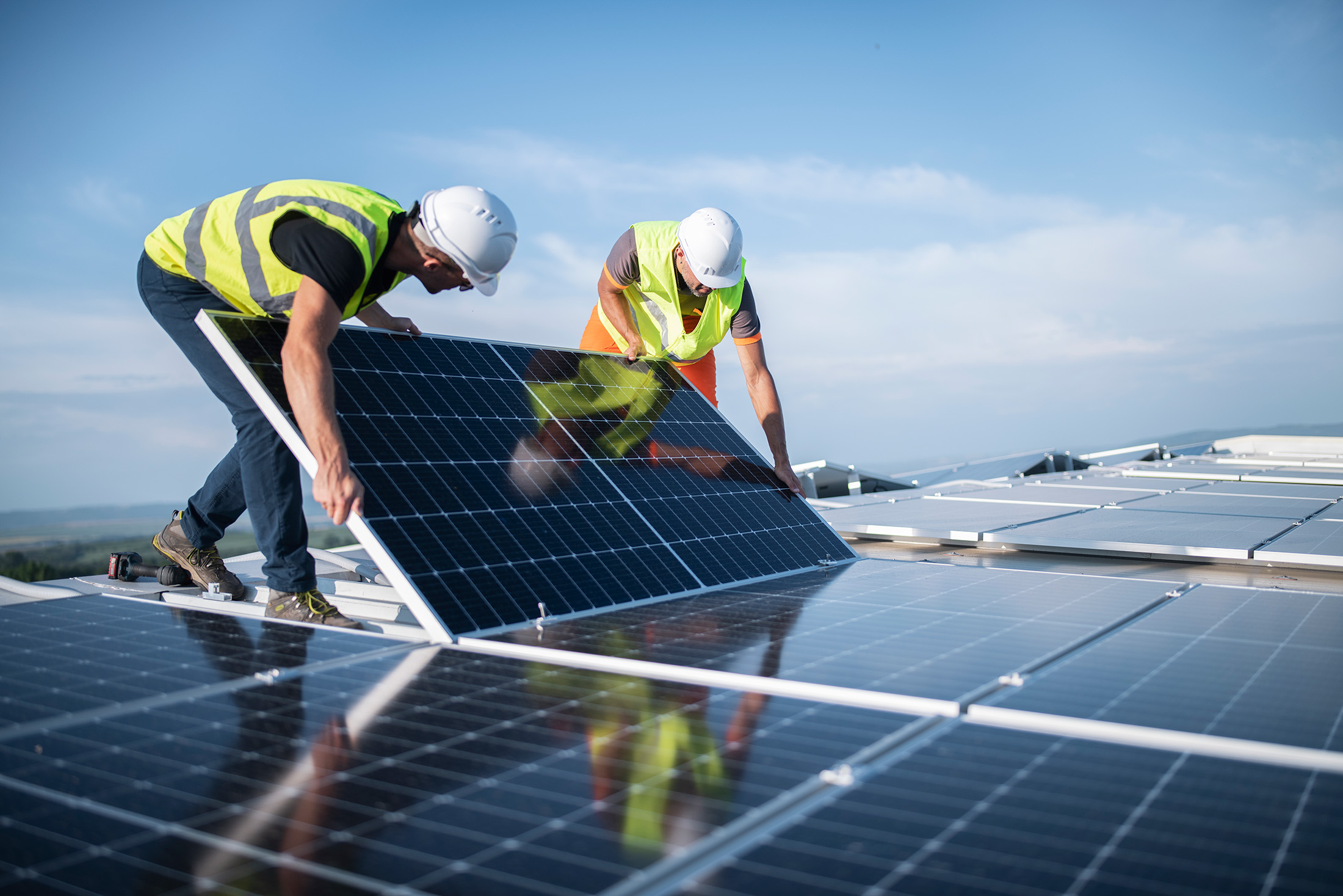 Monteure befestigen ein Solarmodul auf einem Dach